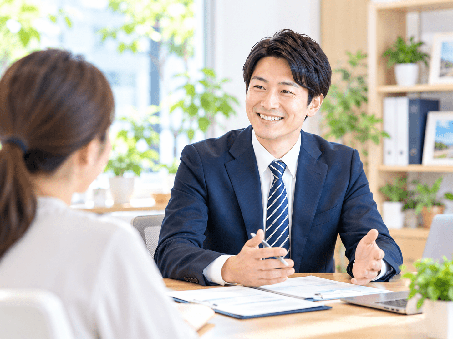 明るい事務所で行政書士が相談者の話を聞いている様子